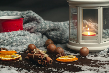 雪木桌上放着燃烧的蜡烛、香料和红杯的灯笼，上面放着热咖啡