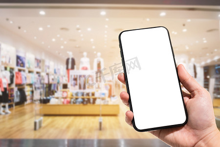 手机联系人摄影照片_女性在商场和服装店背景模糊中使用智能手机的特写模糊图像。