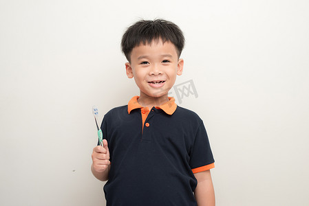 快乐的小男孩在白色背景上拿着牙刷，一个健康的混血男孩的工作室肖像与牙刷隔离。