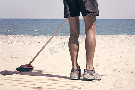 垃圾扫摄影照片_服务人员在海边进行沙滩清洁。