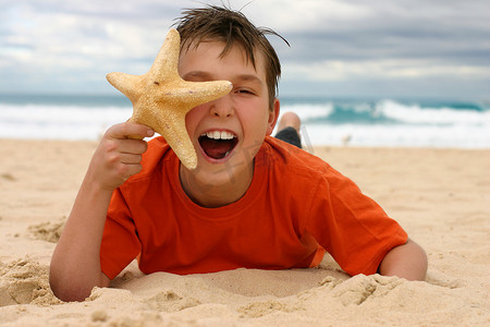 沙滩上拿着海星的笑男孩