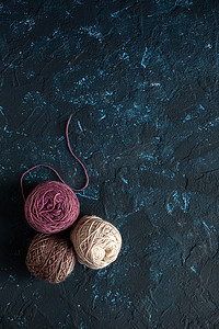 钩毛线摄影照片_深蓝色质地腻子混凝土上用于钩编和针织的羊毛纱线束