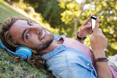 快乐的人躺在草地上用手机听音乐