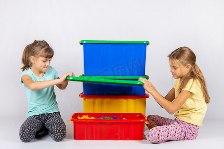两个女孩打开了一个装有玩具的大塑料盒