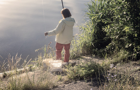 在美丽的湖岸边钓鱼的女人。