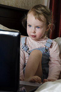 看电视卡通摄影照片_小女孩在笔记本电脑上看起来很卡通