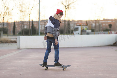 在沥青操场上玩滑板的少年滑板男孩做把戏。