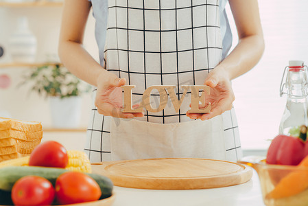 一个女人在厨房里做饭时拿着木制字母 LOVE。