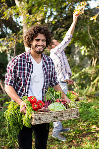 花园里带蔬菜和同事的快乐嬉皮士园丁肖像