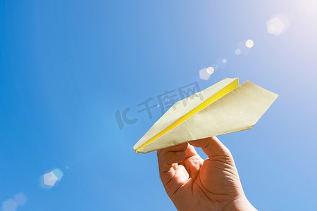 在蓝天和温暖的夏日阳光下玩纸飞机