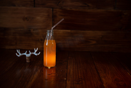 发光鹿角摄影照片_木制背景上的一瓶老式鲜榨果汁和一个发光的符号。