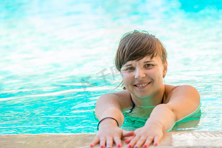 在水里游泳的成人摄影照片_快乐的年轻女孩在游泳池里度过时光