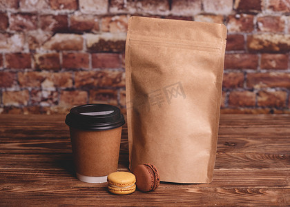 砖摄影照片_木制背景上的一杯咖啡、杏仁饼和牛皮纸袋，靠在砖墙上
