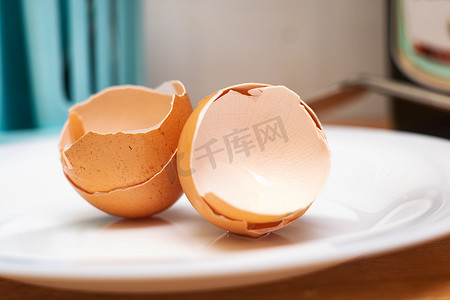 鸡蛋碎了摄影照片_盘子里碎鸡蛋的壳