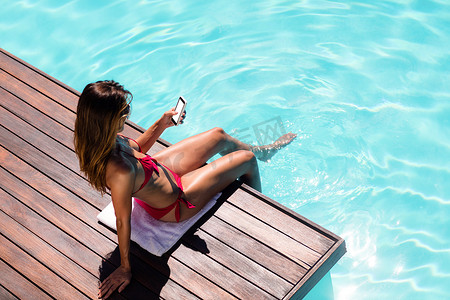 在泳池边使用智能手机的女人