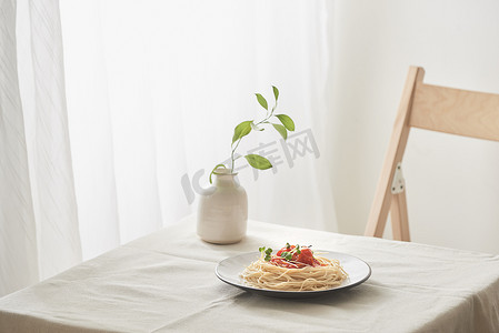 手工制作的意大利面，盘子上放着炖酱，放在老式白桌上，上面放着漏勺和鲜花
