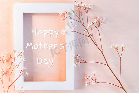 小花装饰摄影照片_珊瑚质感背景上的白色木框，上面有小花和题词“母亲节快乐” — 贺卡