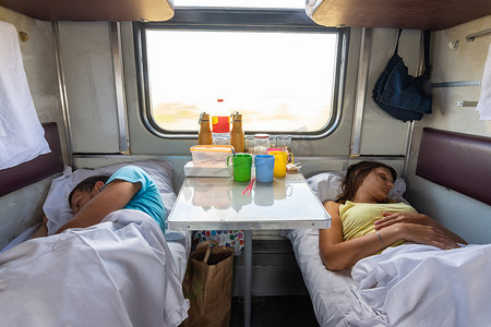 火车底部摄影照片_男人和女人睡在火车车厢的较低架子上