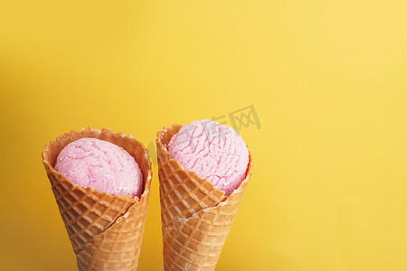 黄色背景中圆锥形的美味粉色冰淇淋。