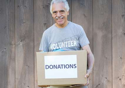 捐款箱摄影照片_拿着捐款箱的微笑的男性志愿者
