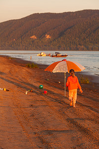 阳光下沿着沙滩奔跑的小女孩