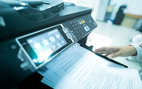 激光摄影照片_办公室工作人员在多功能激光打印机上打印纸张。