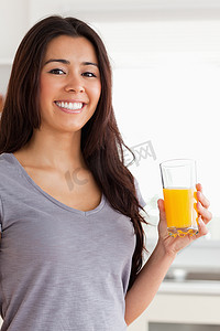 喝酒不贪杯摄影照片_美女站着拿着一杯橙汁