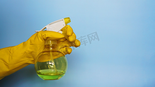 黄色液体摄影照片_手持带清洁剂的黄色橡胶手套手持塑料喷雾瓶