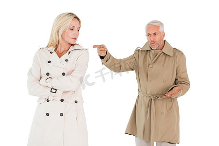 愤怒的夫妻穿着风衣打架