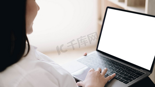 办公室里的女商人在带有样机空白屏幕的笔记本电脑上工作。