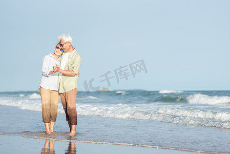 快乐的亚洲老年男女夫妇微笑着跳舞，在沙滩上休息放松