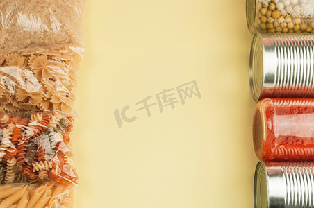 黄色背景顶视图中的一组产品，包括面食、米饭、饼干、番茄酱、豌豆和罐头食品。
