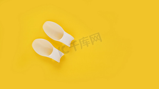 拇指外翻摄影照片_黄色背景上的白色硅胶手指分隔器