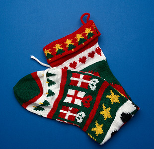 蓝色礼物摄影照片_针织色彩鲜艳的圣诞袜子，用于蓝色背面的礼物