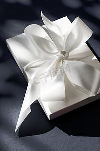 黑色背景中带丝带和蝴蝶结的豪华假日白色礼盒、豪华婚礼或生日礼物