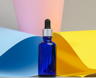 蓝色玻璃透明瓶，彩色背景上带有吸管。
