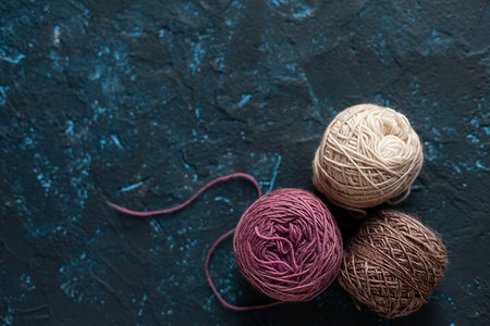 钩毛线摄影照片_深蓝色质地腻子混凝土上用于钩编和针织的羊毛纱线束