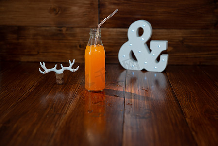 发光鹿角摄影照片_木制背景上的一瓶老式鲜榨果汁和一个发光的符号。