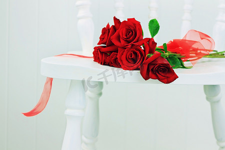 弗洛雷斯玫瑰摄影照片_白椅子上的红玫瑰