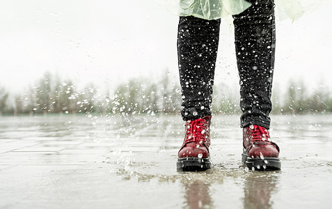 女人在雨中玩耍，在溅起的水坑中跳跃