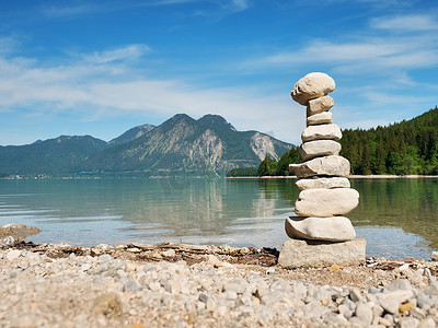 石湖摄影照片_鹅卵石湖滩上的扁平石头金字塔，地平线上的群山