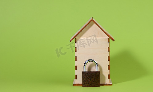 绿色背景中的微型木屋和金属锁，安全概念