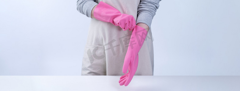 围裙的年轻女管家戴着粉色手套清洁桌子，预防病毒感染的概念，家政服务，特写。