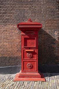 靠着砖墙站立的红色旧荷兰邮箱