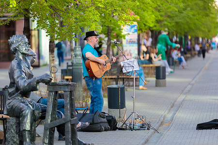 一个头发花白的成年男子在城市街道上弹吉他唱歌。