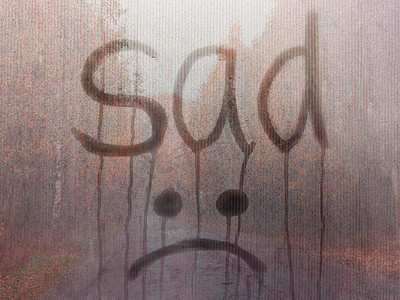 在秋天风景的背景下，由悲伤和表情符号写在雾蒙蒙的玻璃上。