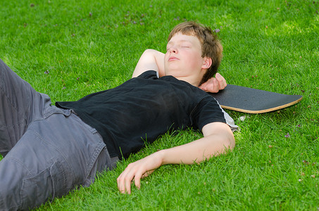 有冰鞋的少年在草地上休息