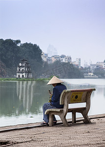 航空宣传摄影照片_越南河内 — 2012 年 3 月：坐在长凳上的女人