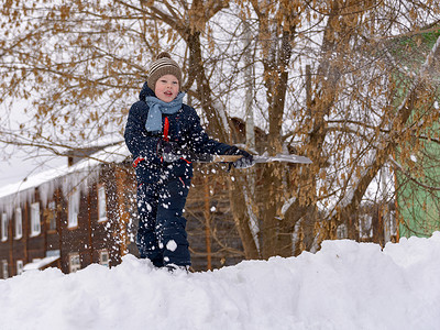 一个戴着针织帽、戴着围巾的男孩在冬天在雪地里玩耍。