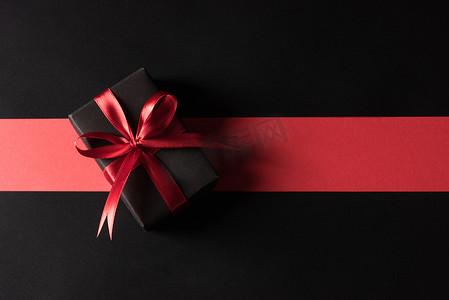 蝴蝶结黑色红色摄影照片_礼品盒包装黑纸和黑色蝴蝶结丝带礼物